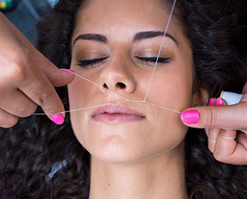 woman on facial hair removal threading procedure